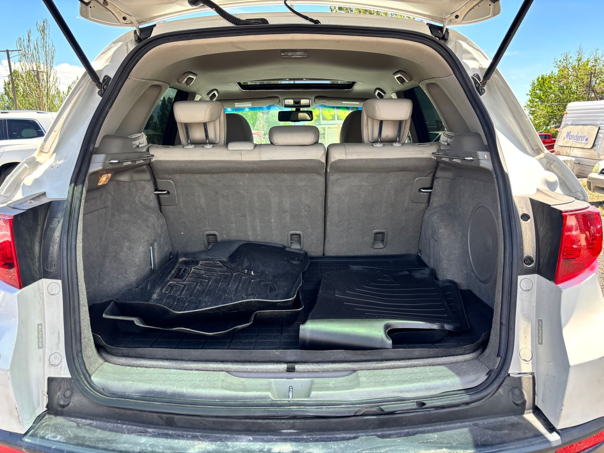 Open car trunk with folded rear seats and cargo area, black floor mats inside.