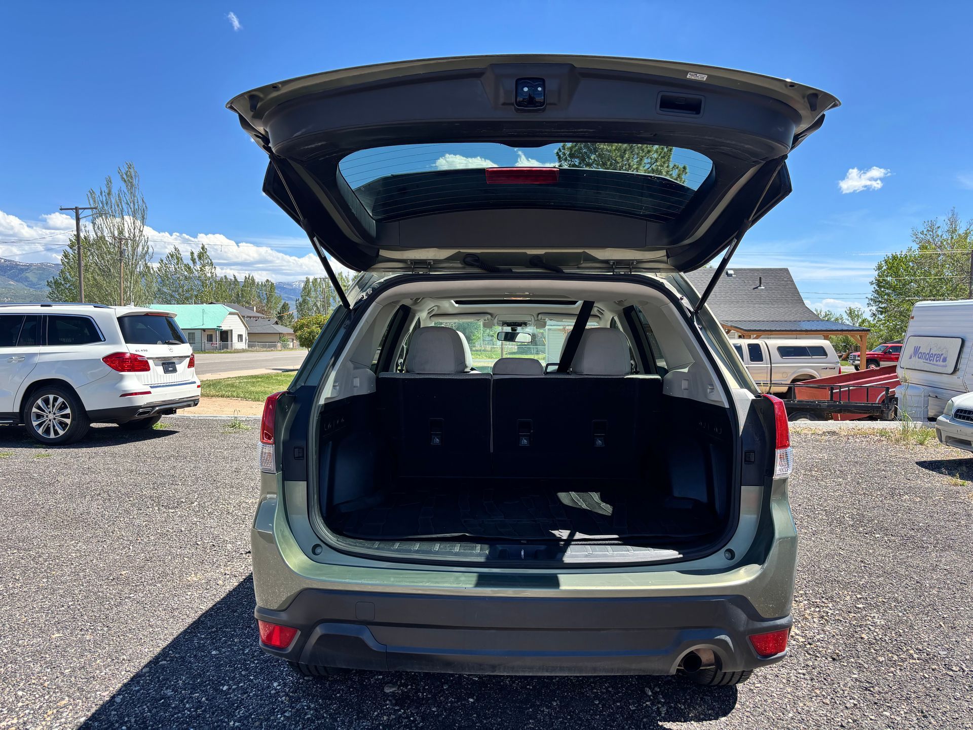 Open hatch of a green SUV parked on gravel in a lot