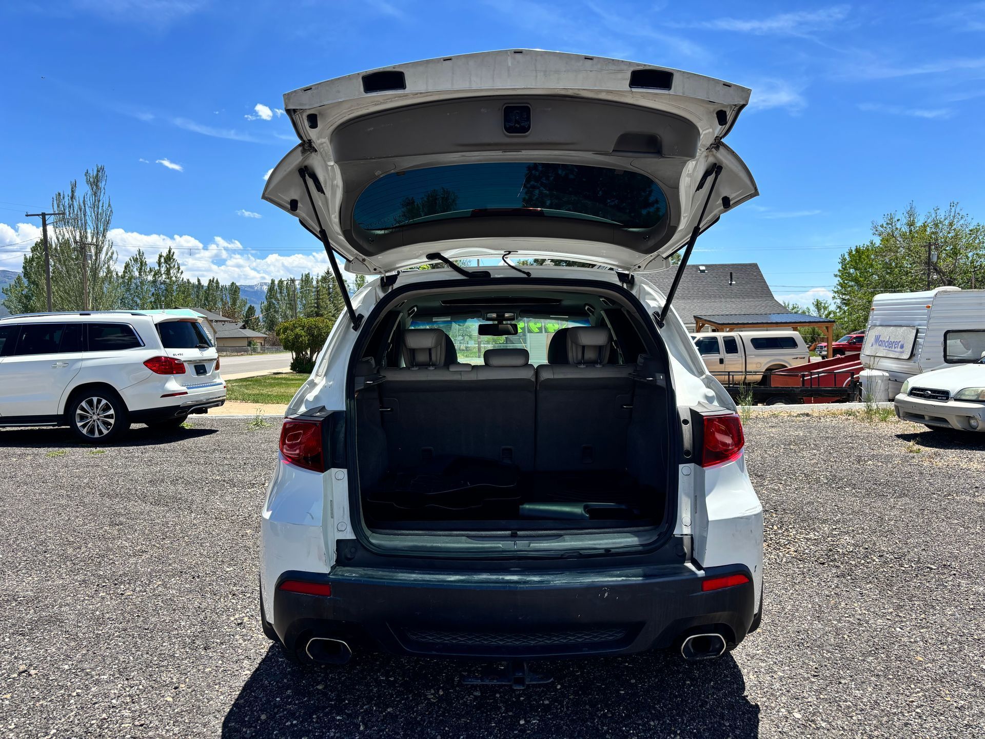Open SUV hatch with empty cargo area in a gravel parking lot