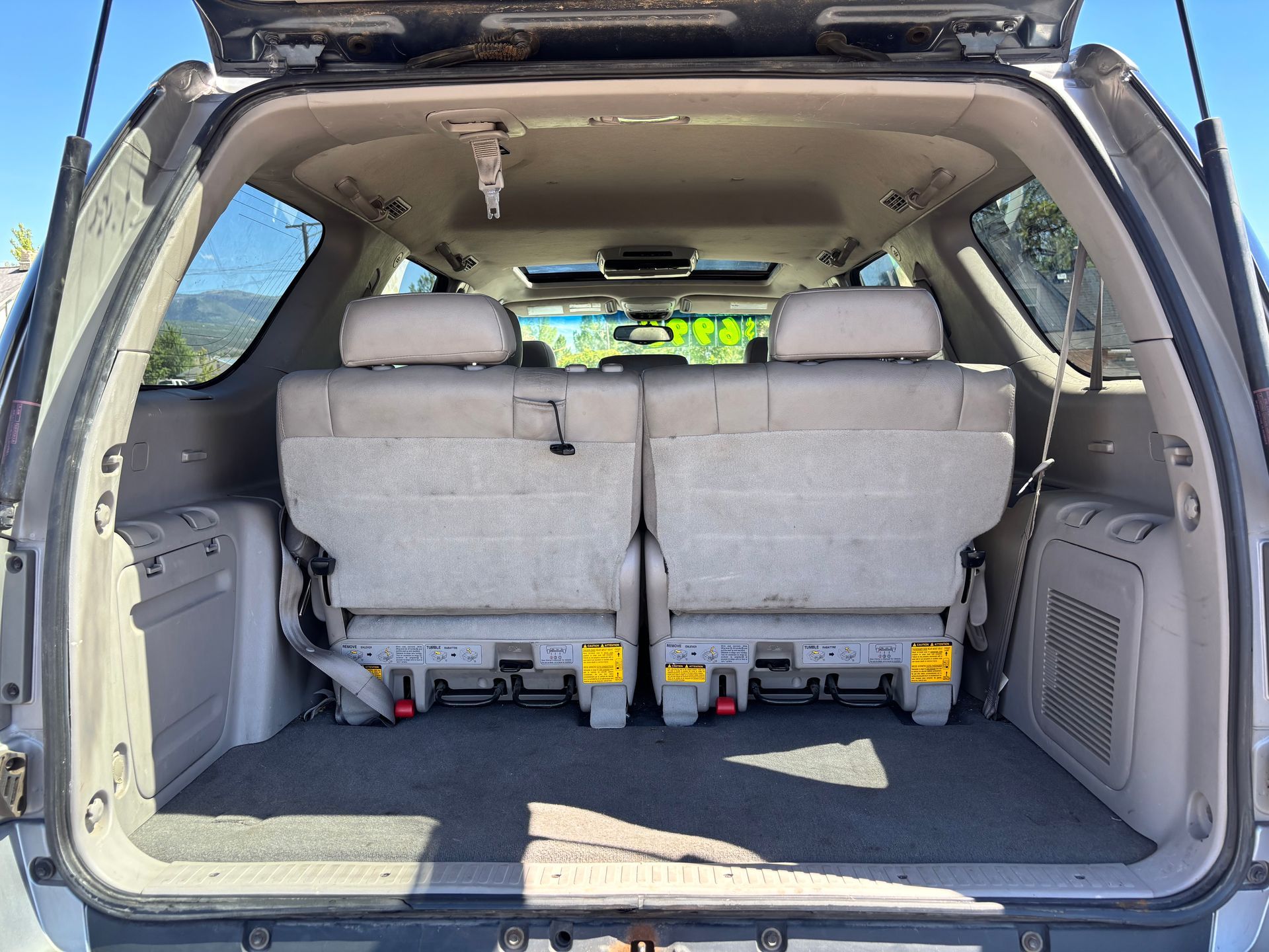Open SUV cargo area with third-row seats folded up and rear hatch raised