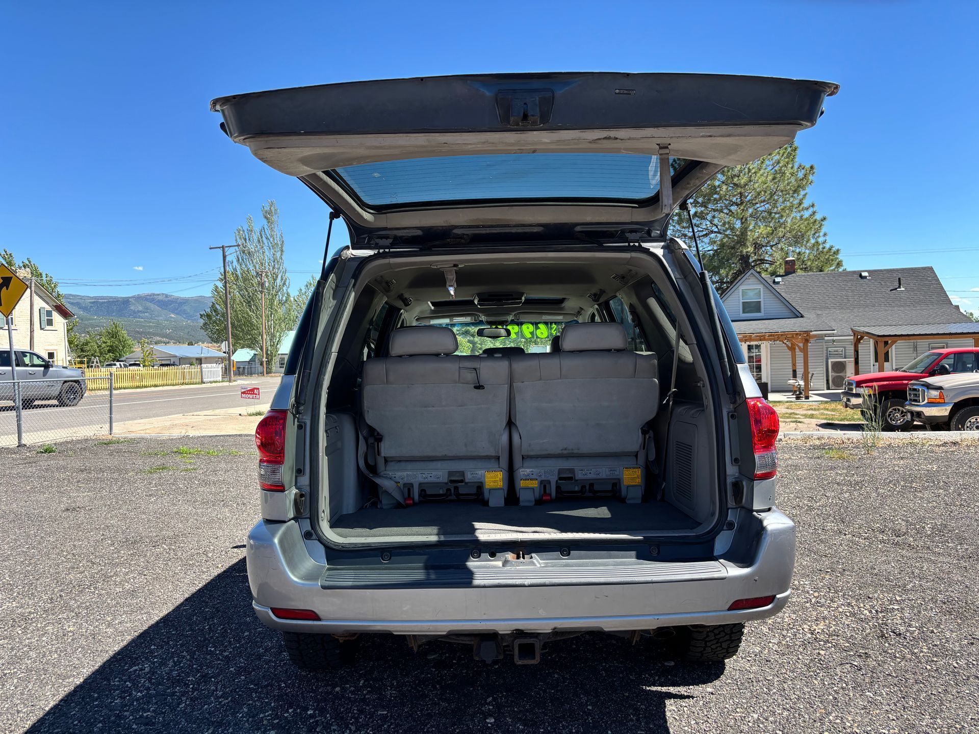 Open SUV trunk with rear seats folded down, parked on gravel under a clear blue sky.