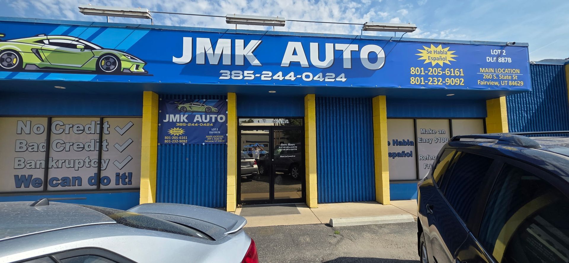 JMK Auto storefront with blue sign, yellow trim, and parked cars in front