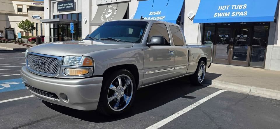 Silver pickup truck parked on a street in front of shops on a sunny day
