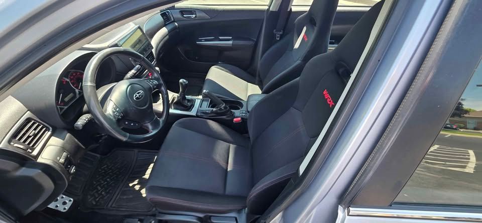 Black car interior with steering wheel and front seats, driver door open, dashboard visible.