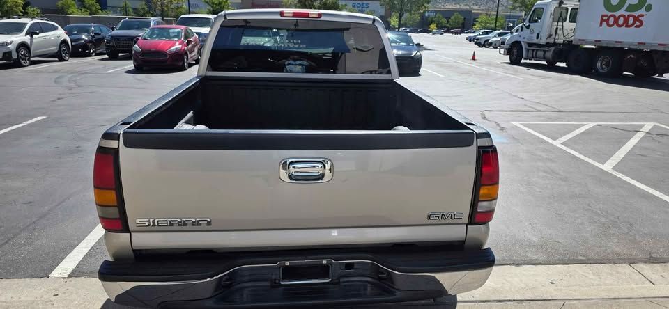 Beige Dodge pickup truck with open bed, viewed from behind in a parking lot