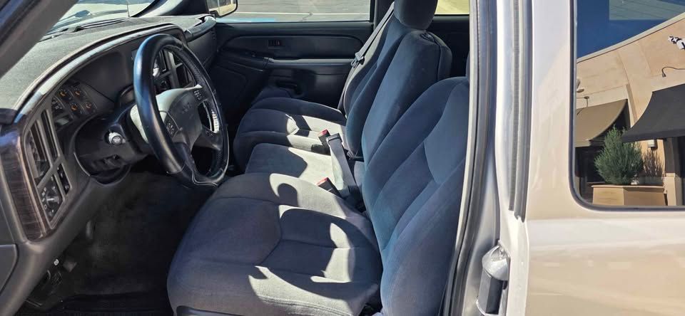Car interior with gray cloth front seats and steering wheel, viewed from the open driver’s door