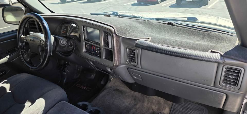 Inside an older vehicle, showing the driver’s seat, dashboard, steering wheel, and front passenger area.