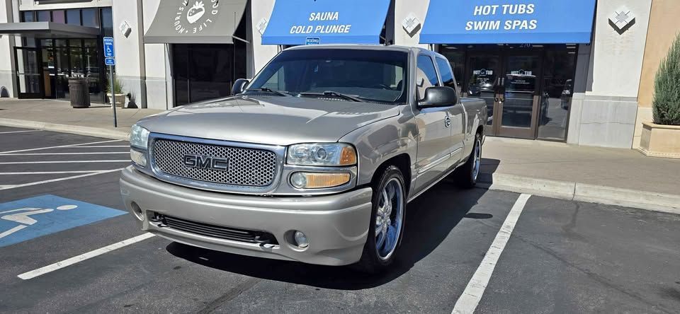 Silver pickup truck parked in front of a building with blue awnings and handicap parking markings
