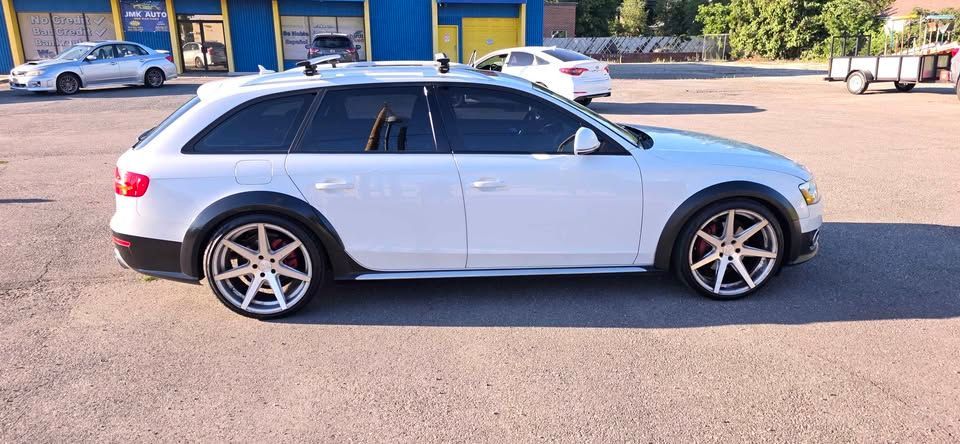 White station wagon parked in a lot, side view
