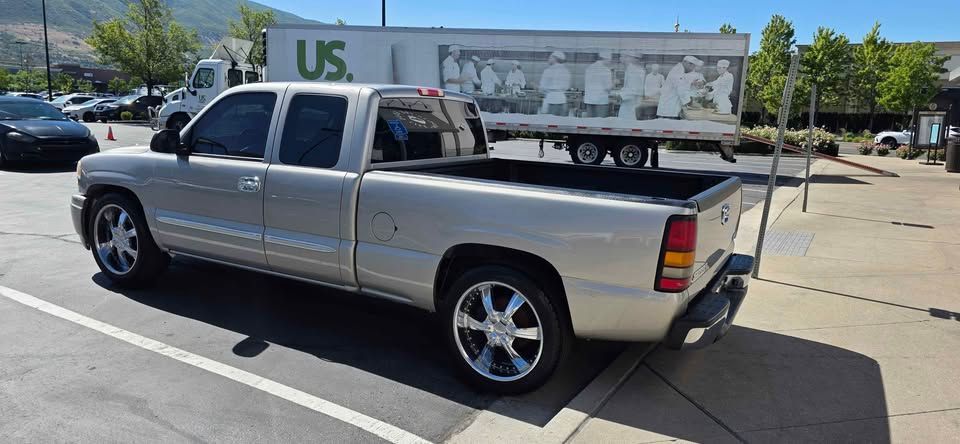 Silver pickup truck parked in a lot beside a white U.S. trailer under a clear sky