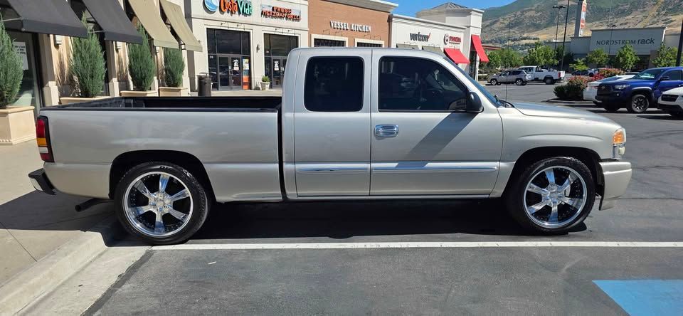 Silver pickup truck parked on a street in front of storefronts and mountains