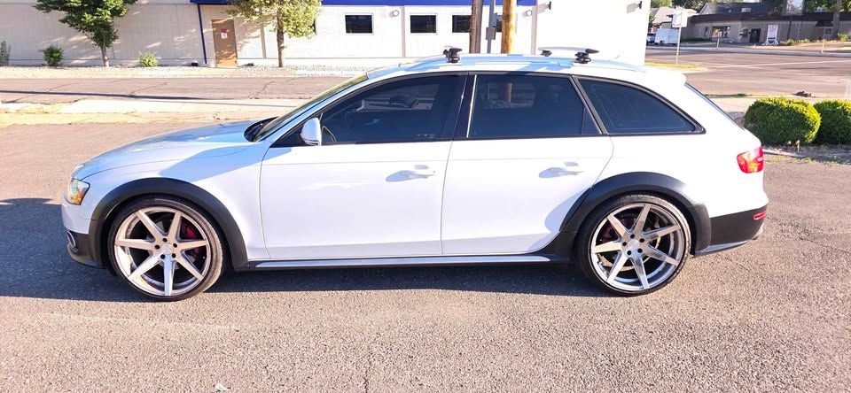 White station wagon parked on a sunny street, side view, with tinted windows and alloy wheels