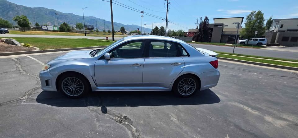 Silver sedan parked on an asphalt lot with mountains and buildings in the background