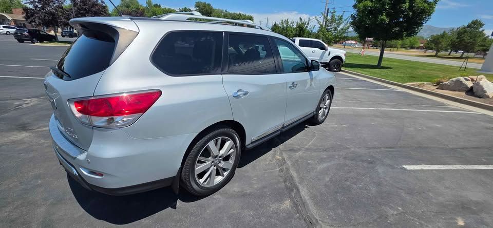 Silver SUV parked in a sunny parking lot with other cars and trees nearby