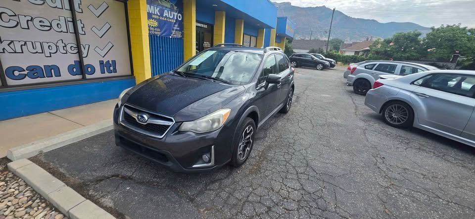 Black SUV parked outside a blue building in a parking lot with other cars and mountains in the background