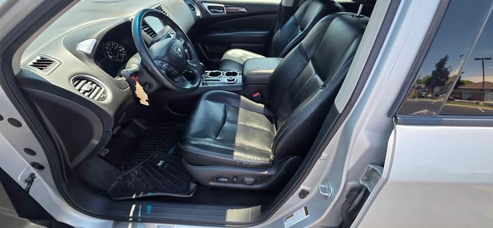 Open car door showing black leather front seats, dashboard, and steering wheel on a silver vehicle