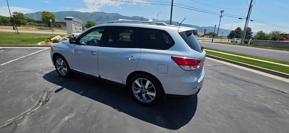 Silver SUV parked on a sunny paved lot near a road and grassy median
