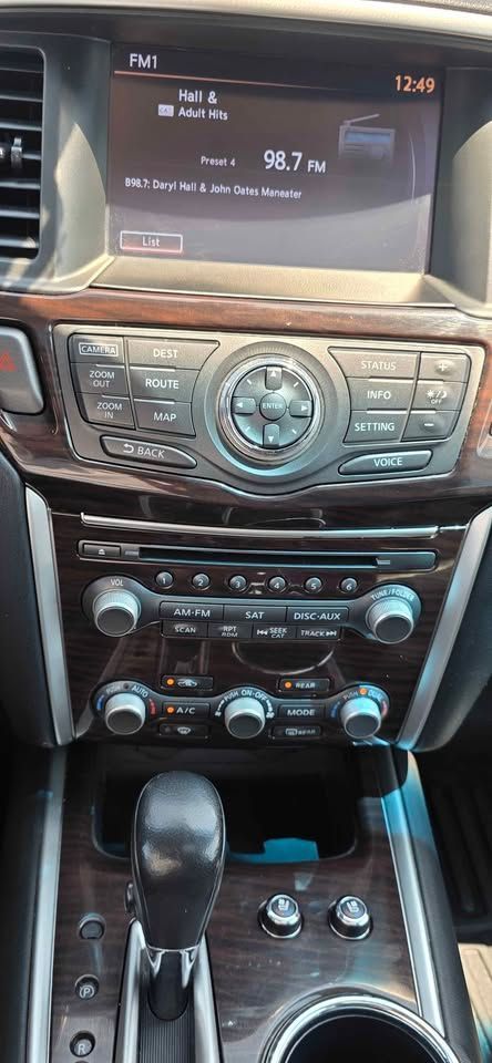 Car interior center console with touchscreen display, radio controls, climate knobs, gear shifter, and cupholders.