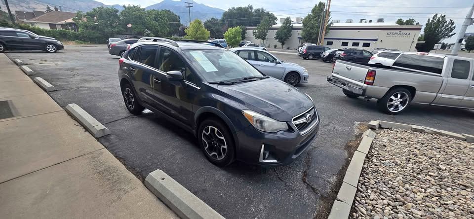 Dark gray SUV parked in a lot beside a curb, with mountains and other vehicles in the background
