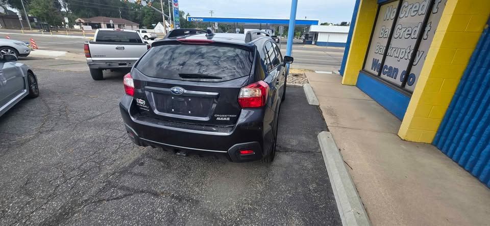 Black SUV parked crooked in a gas station lot beside a curb and blue-yellow building.