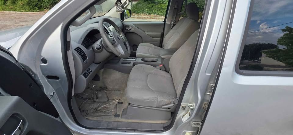 Open car door showing a gray interior with the front seat and floor visible.