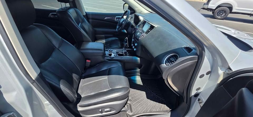 Car interior with black leather seats and center console, viewed from the open passenger door