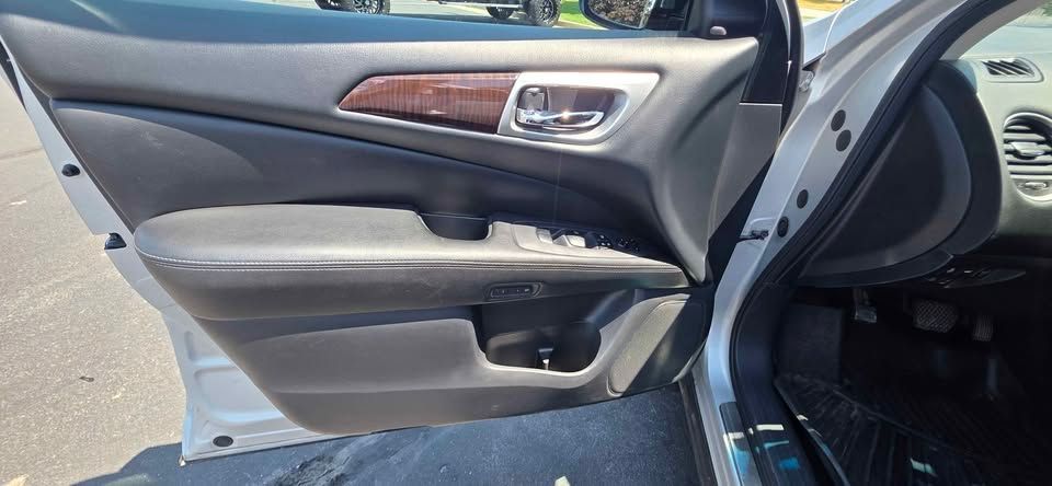 Open car door with black leather panel, wood trim, and silver handle, showing the interior.