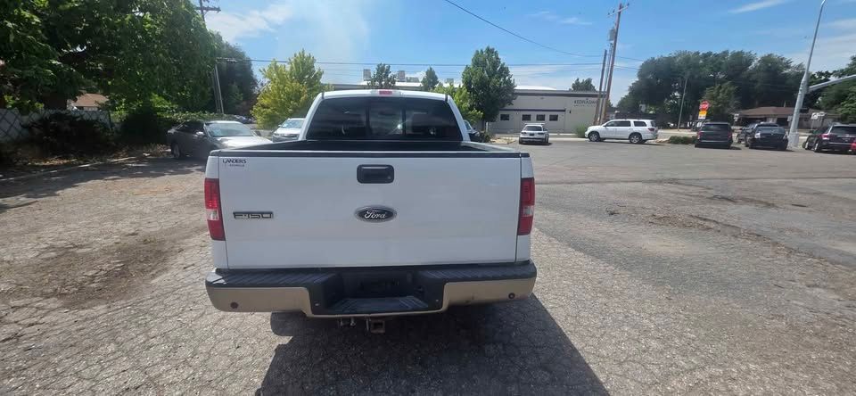 White Ford pickup truck viewed from the rear in a parking lot on a sunny day