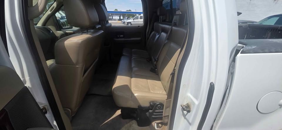 Open car door showing beige back seat interior and front seat from outside.
