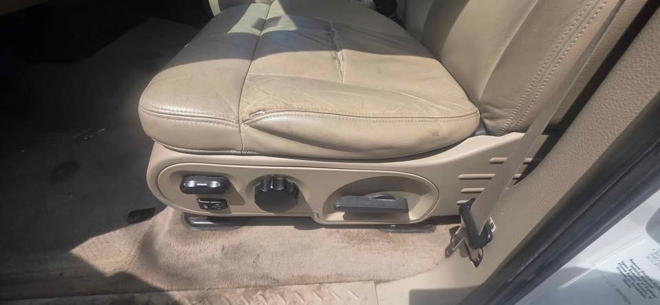 Beige car front passenger seat and power controls with tan upholstery in daylight