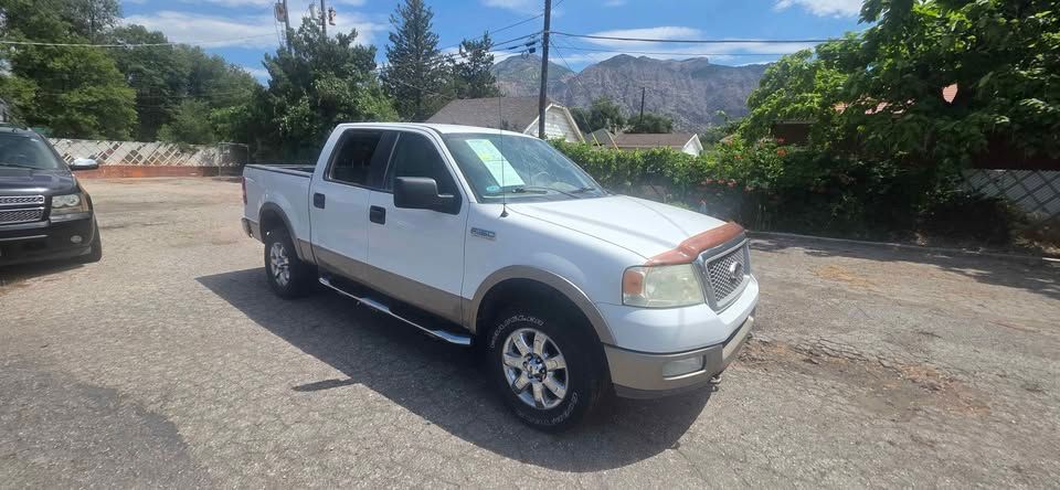 White pickup truck parked on a gravel lot with mountains and trees in the background