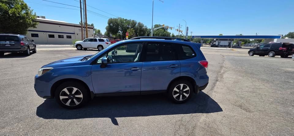 Blue SUV parked in a sunny lot near a road under a clear sky