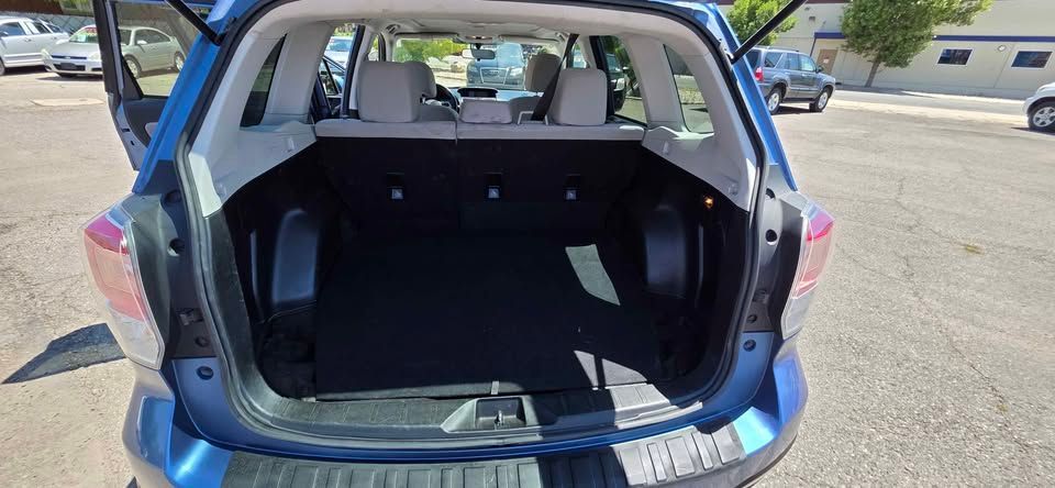 Open hatch of a blue hatchback showing a mostly empty trunk in a parking lot