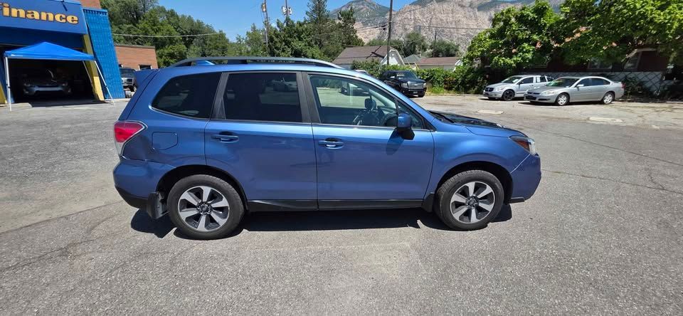 Blue SUV parked in a sunlit lot near an auto dealership