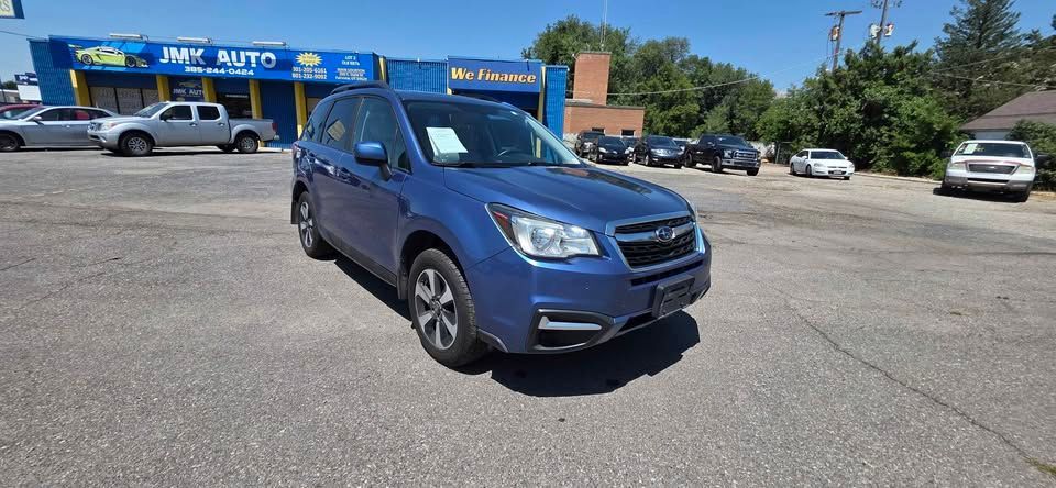 Blue SUV parked on a sunny used car lot with dealership buildings in the background