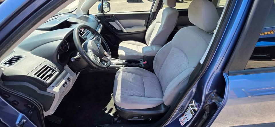 Car interior with black and beige seats, steering wheel, and center console in daylight.