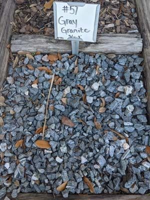 Sample of gray granite gravel labeled “#57 Gran Granite” in a display bin