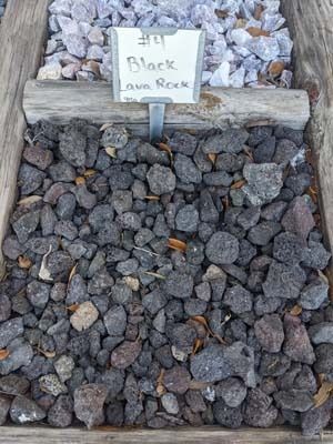 Rustic sign reading “Black onyx rock” above a pile of dark stones in a display