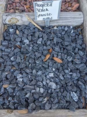 Blue-gray crushed stone mulch beneath a small handwritten plant label and wooden edging.