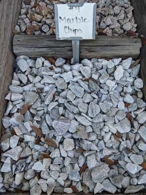 White marble chips in a garden bed with a small sign labeled “Marble Chips”