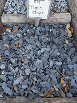 Bin of gray slate chips with a small sign above them outdoors
