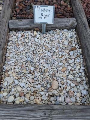 White river rock sample display in a wooden frame with a small label sign at the top.