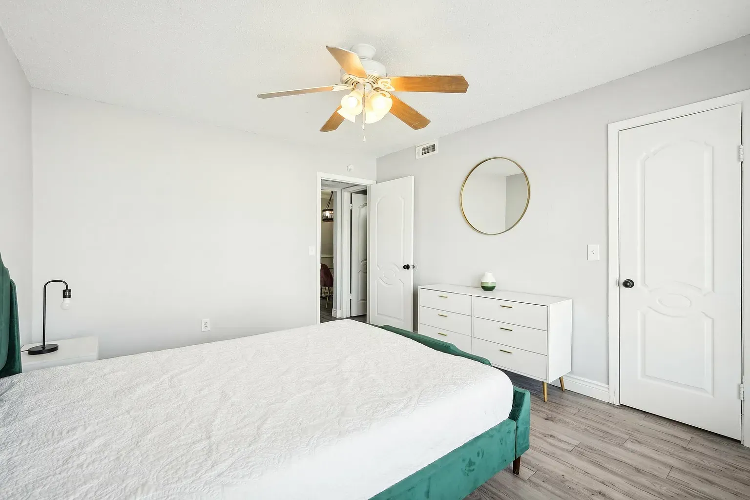Bright bedroom with a teal bed frame, ceiling fan, and white dresser.