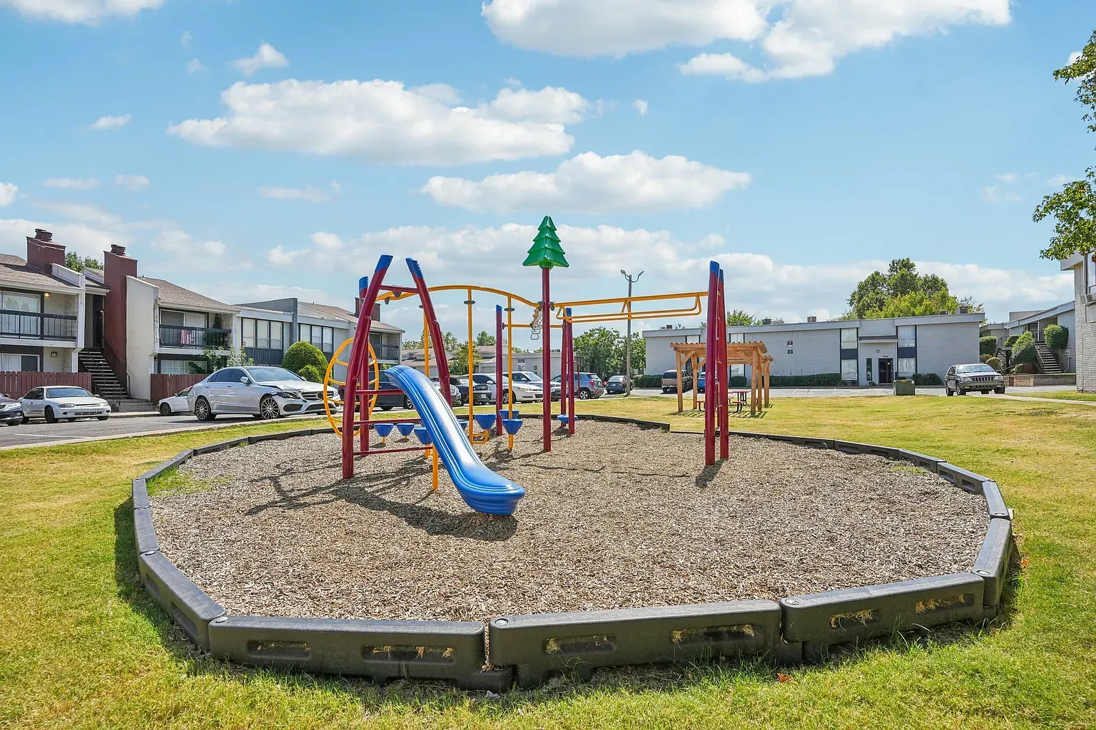 Colorful playground with slide and climbing structures in an apartment community yard.