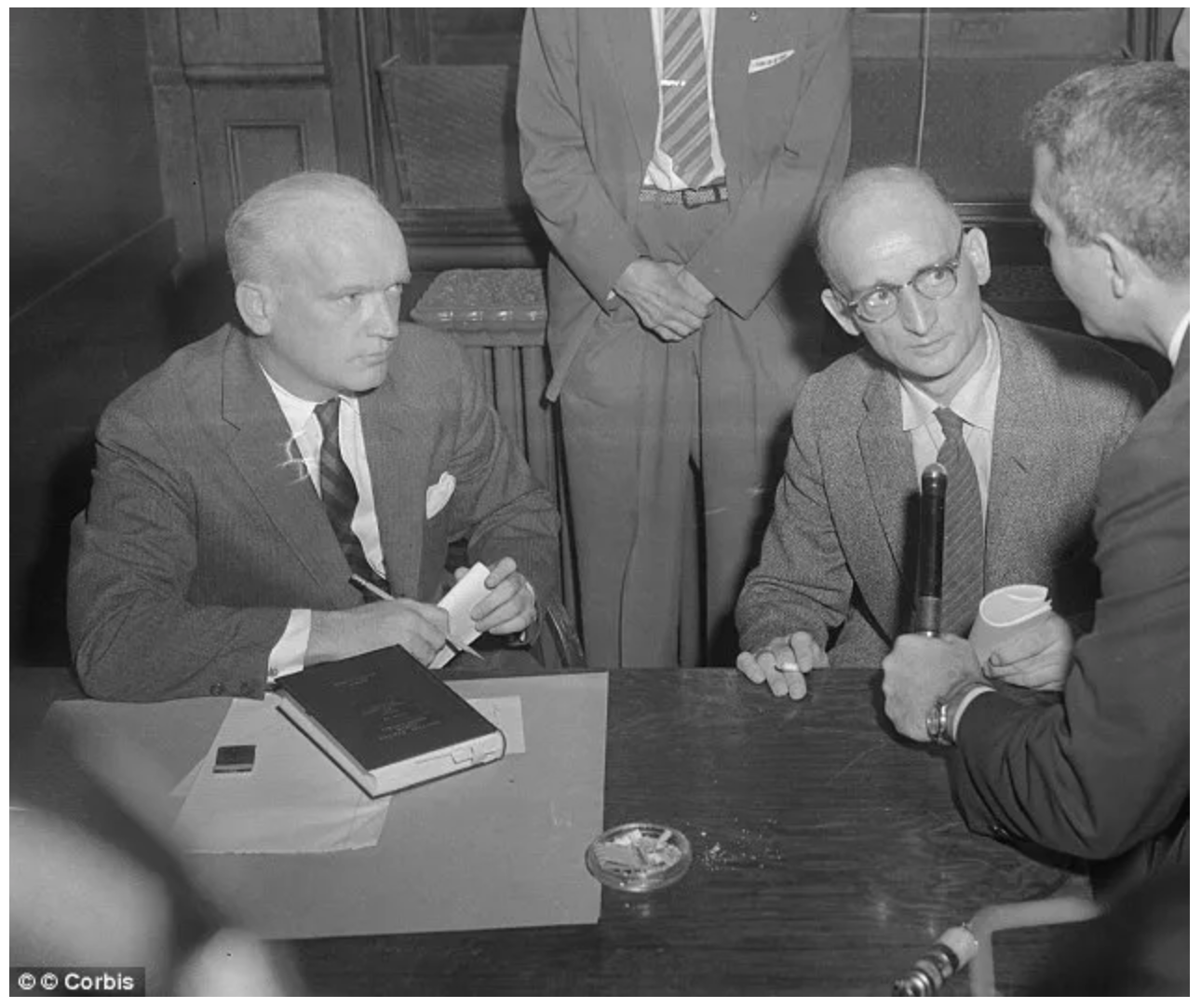 A group of men are sitting at a table talking to each other.