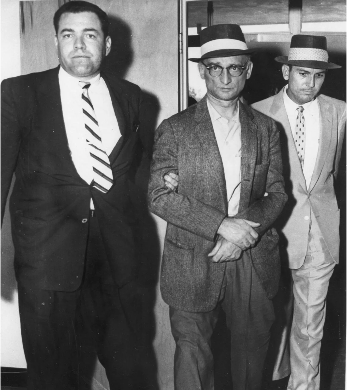 Three men in suits and hats are standing next to each other