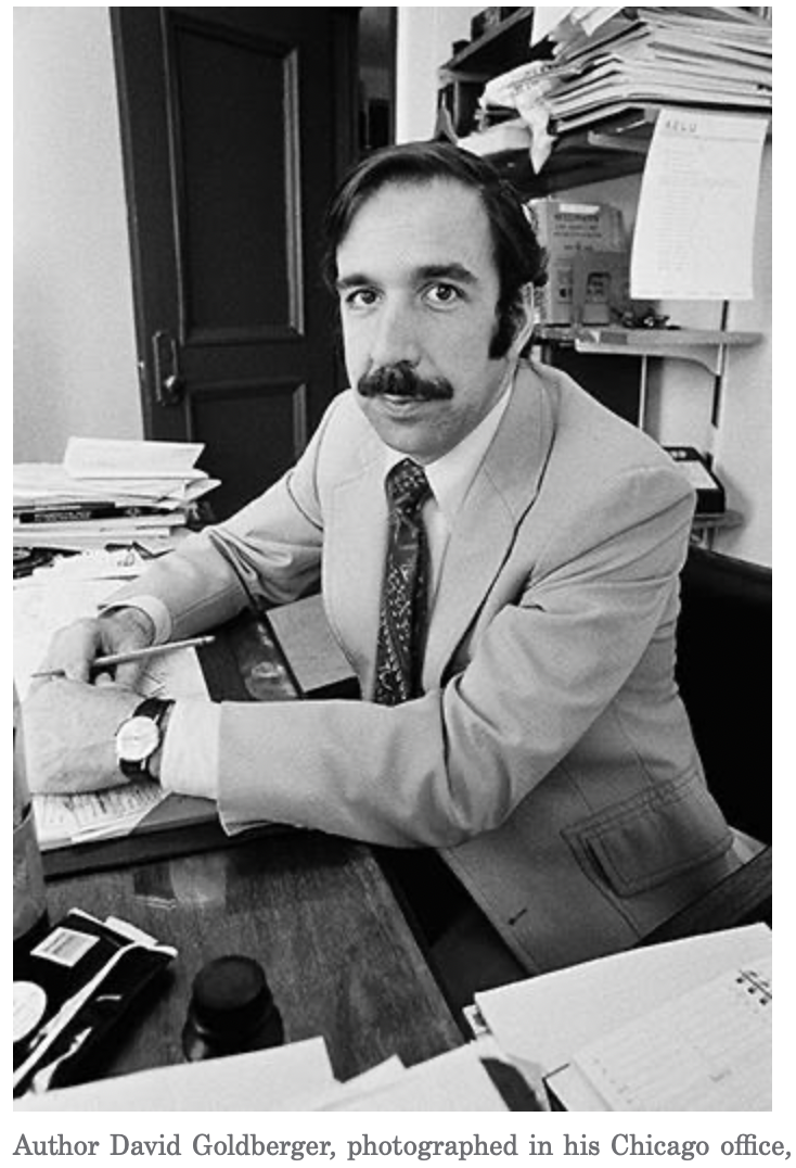 A man in a suit and tie is sitting at a desk