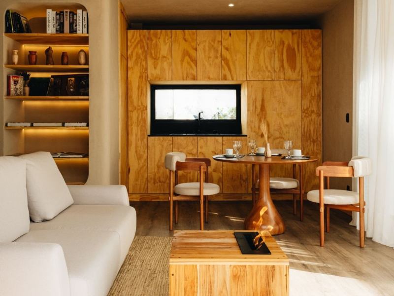 Sala de estar moderna com sofá branco, parede com detalhes em madeira, prateleiras, mesa de jantar e pequena lareira.