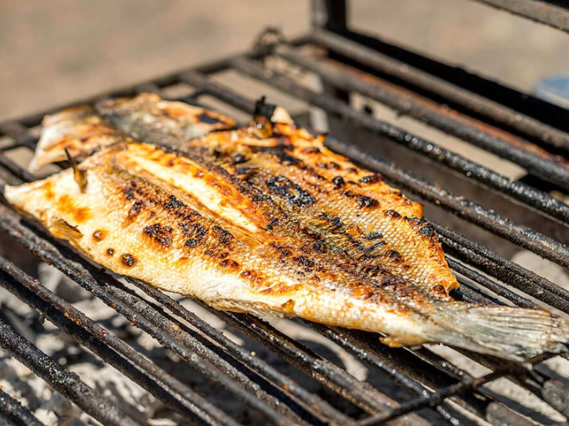 Filé de peixe grelhado com marcas de grelha, cozinhando na grelha da churrasqueira.