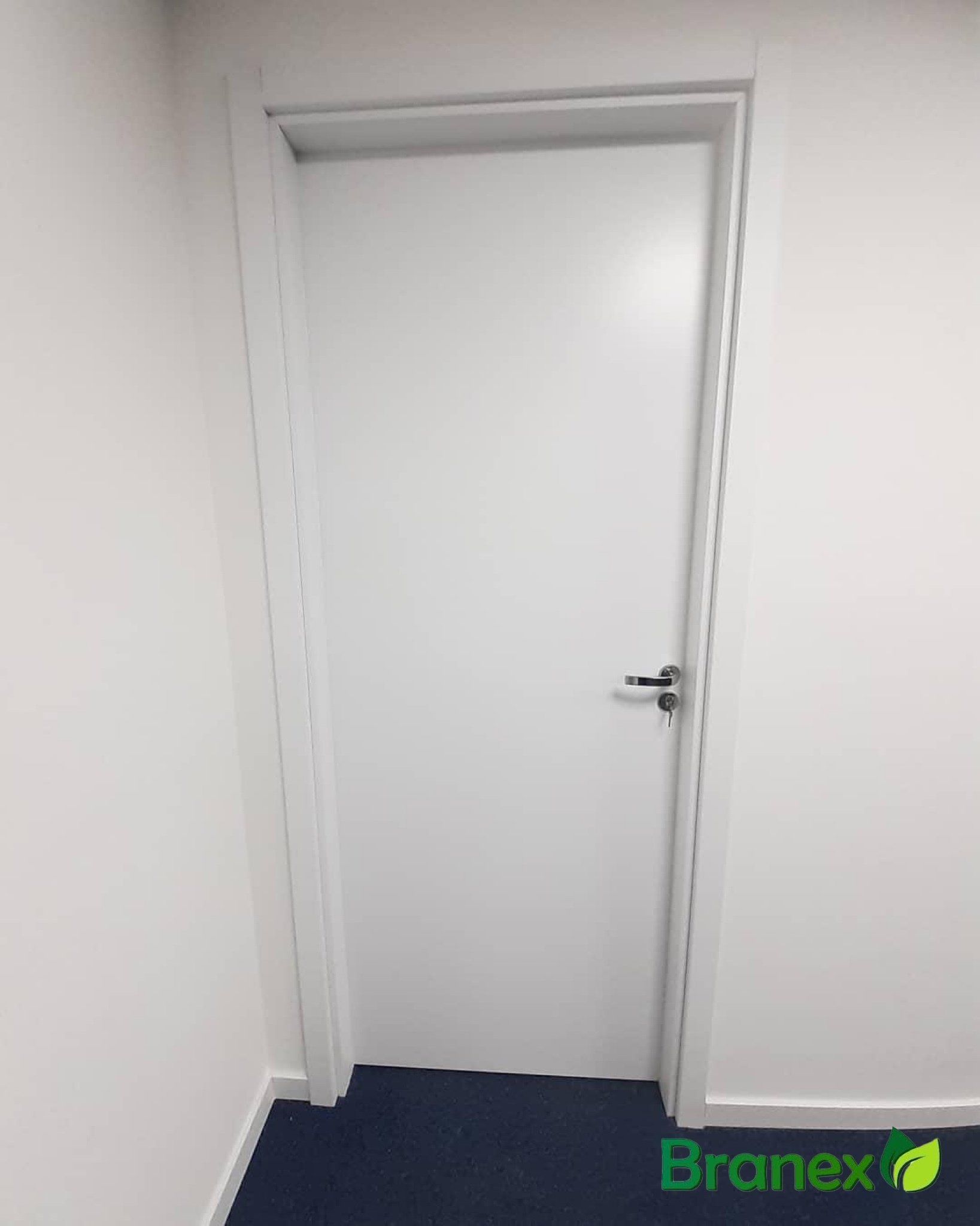 Uma porta branca está em uma sala com um tapete azul.